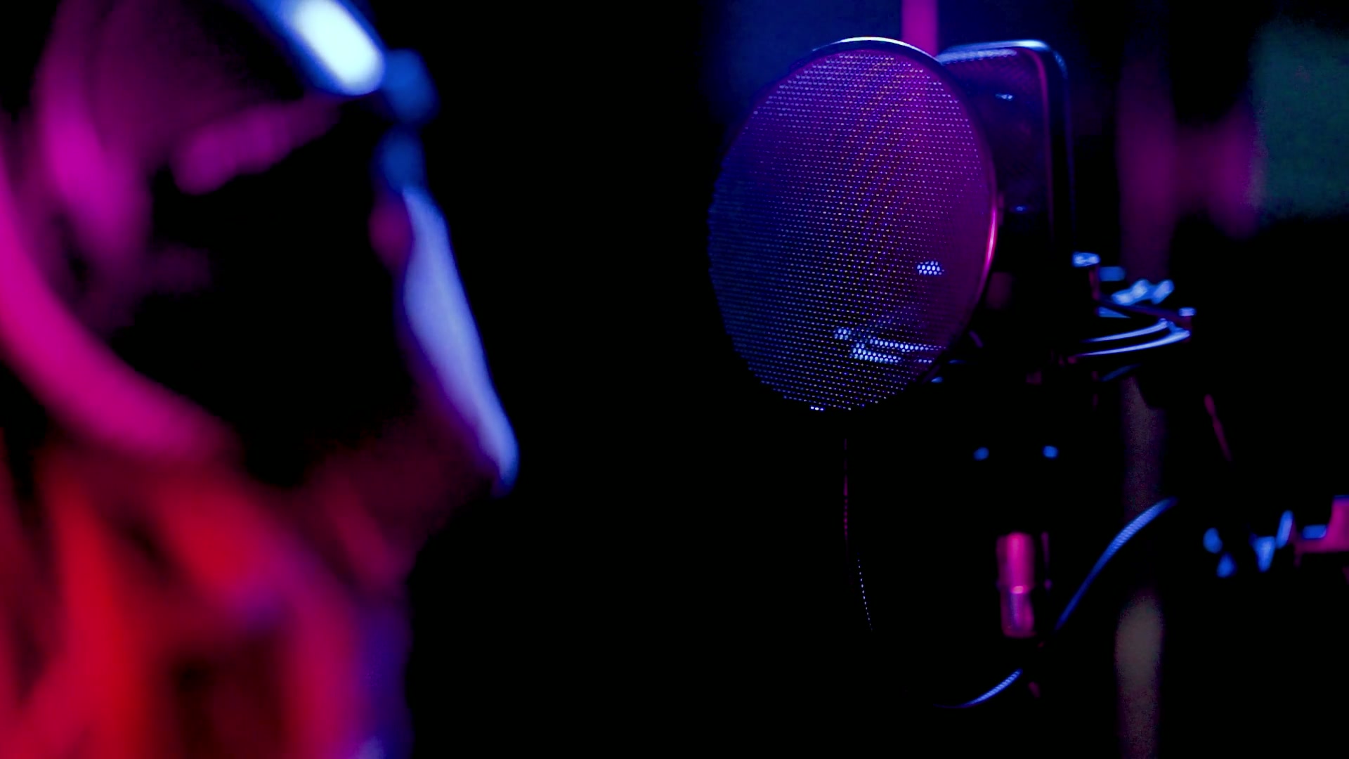 Singer recording vocals in front of a condenser microphone